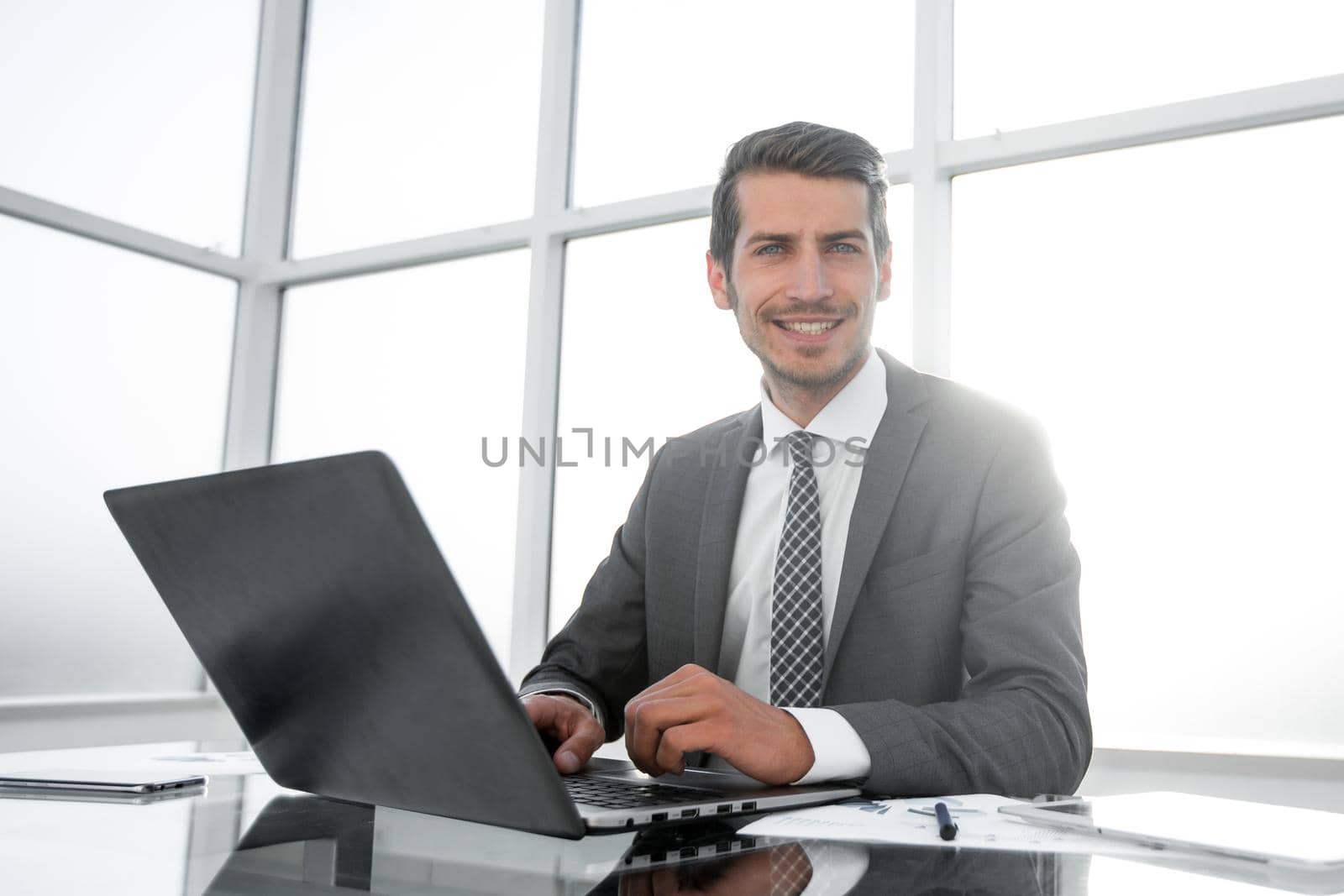 smiling businessman sitting at his Desk. people and technology