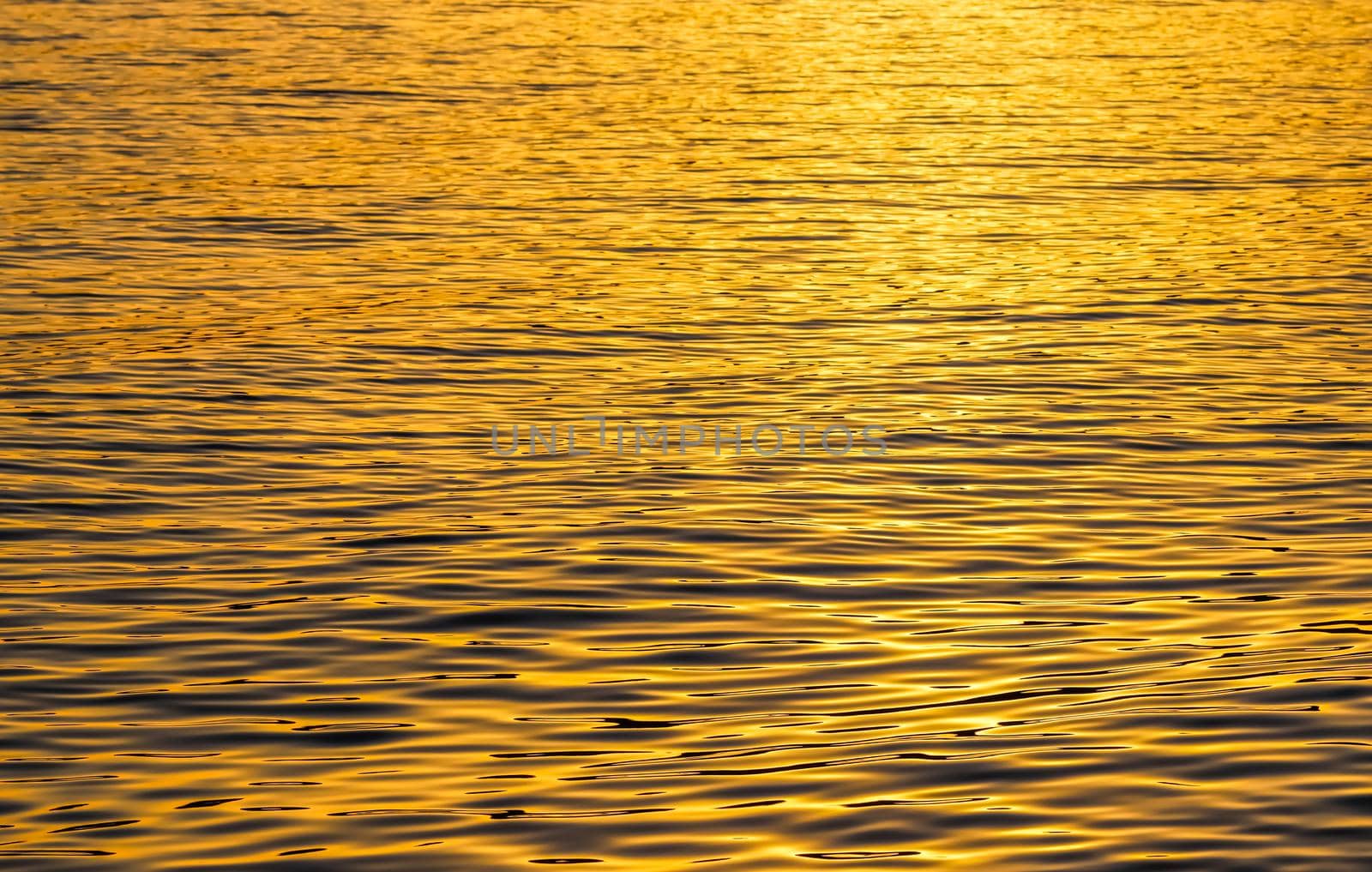 Golden sea waves in sunset glow as surface background. Summer holidays and coastal nature concept