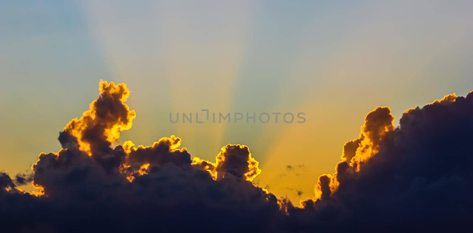 Background from a beautiful sunset with clouds and sunlights over mountanous coast. High quality photo