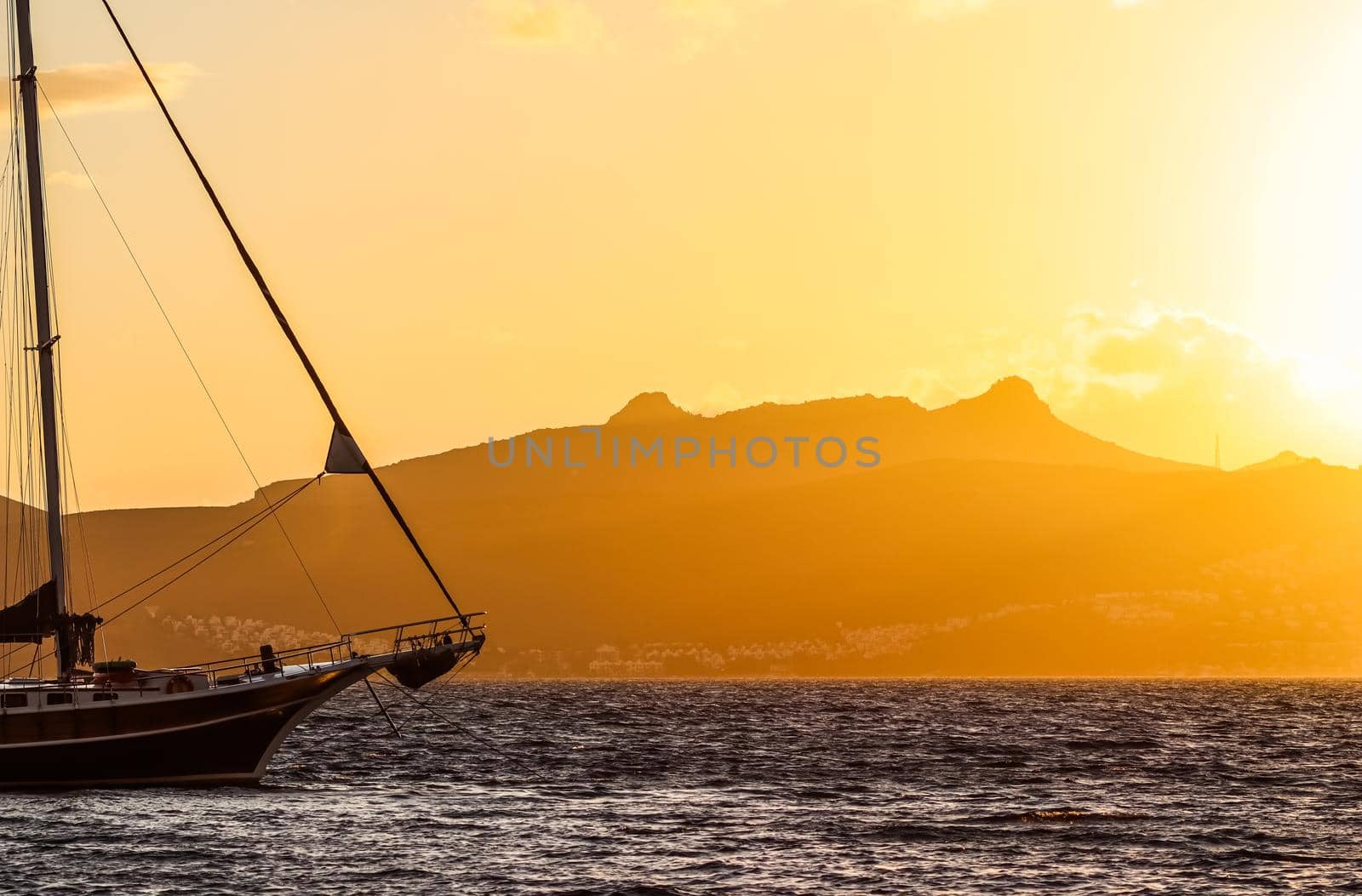 Beautiful sunset on the Aegean Sea with mountains and a sailboat. Seascape, travel and nature concept. High quality photo