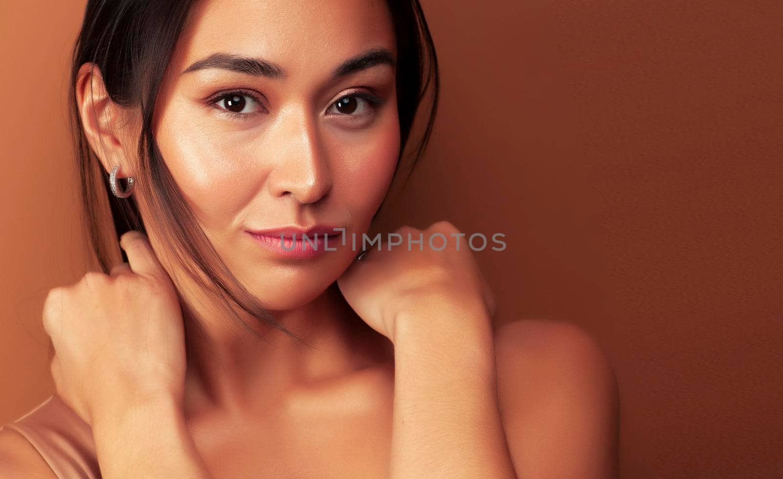 young pretty asian woman cheerful smiling posing on warm brown background, lifestyle people concept close up