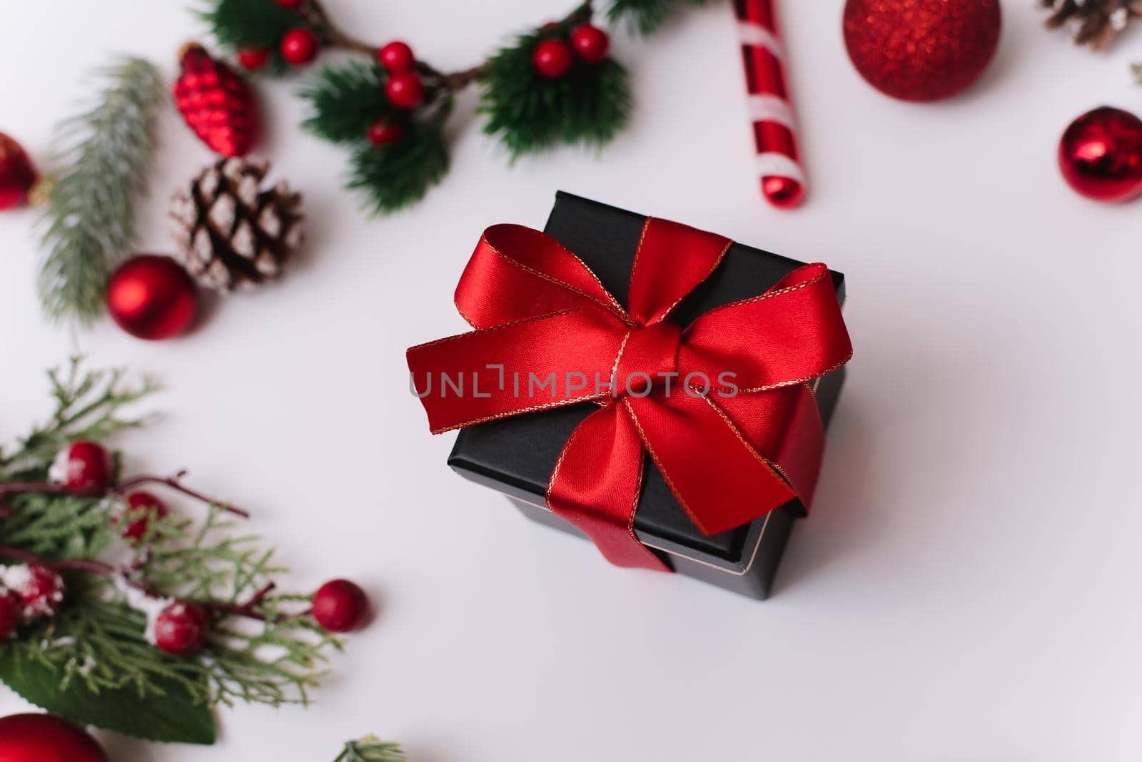 New Year or Christmas composition on a white background with a gift box, with a red ribbon with fir branches, toys, copy space for congratulations.