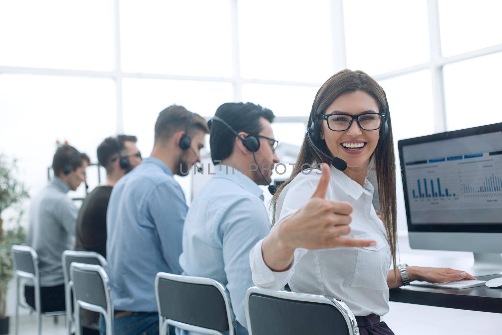 smiling employee of the business centre showing thumb up . success concept