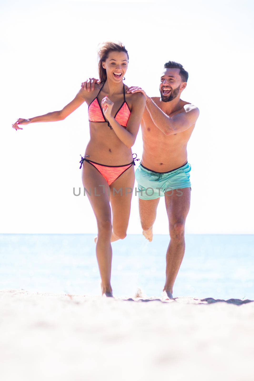 Couple having fun running throughsand on beach. by asdf