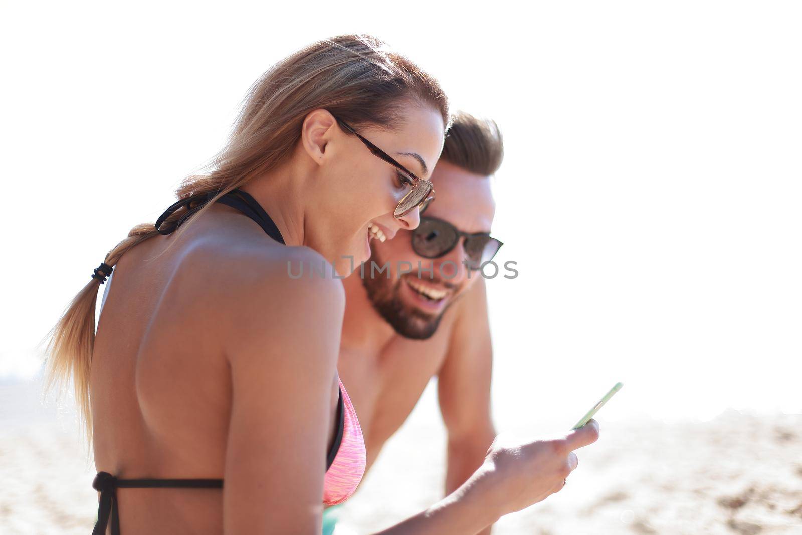 Romantic couple browsing their photos on the beach