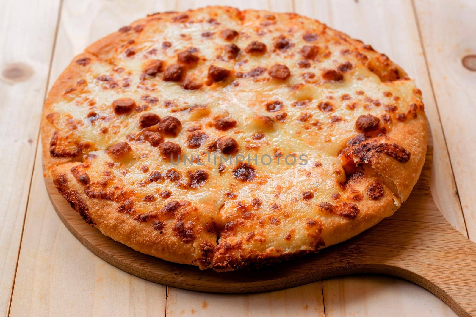 Closeup selective focus of the pizza on a wooden tray on a wooden table.