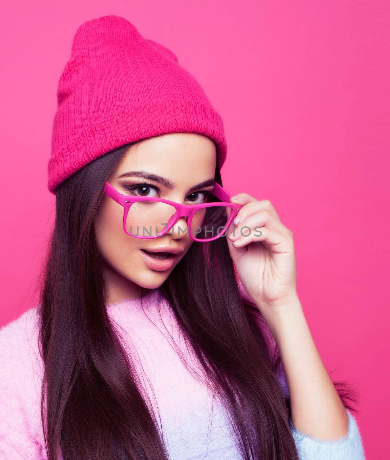 young pretty girl with brunette long hair posing cheerful on pink background, lifestyle people concept close up