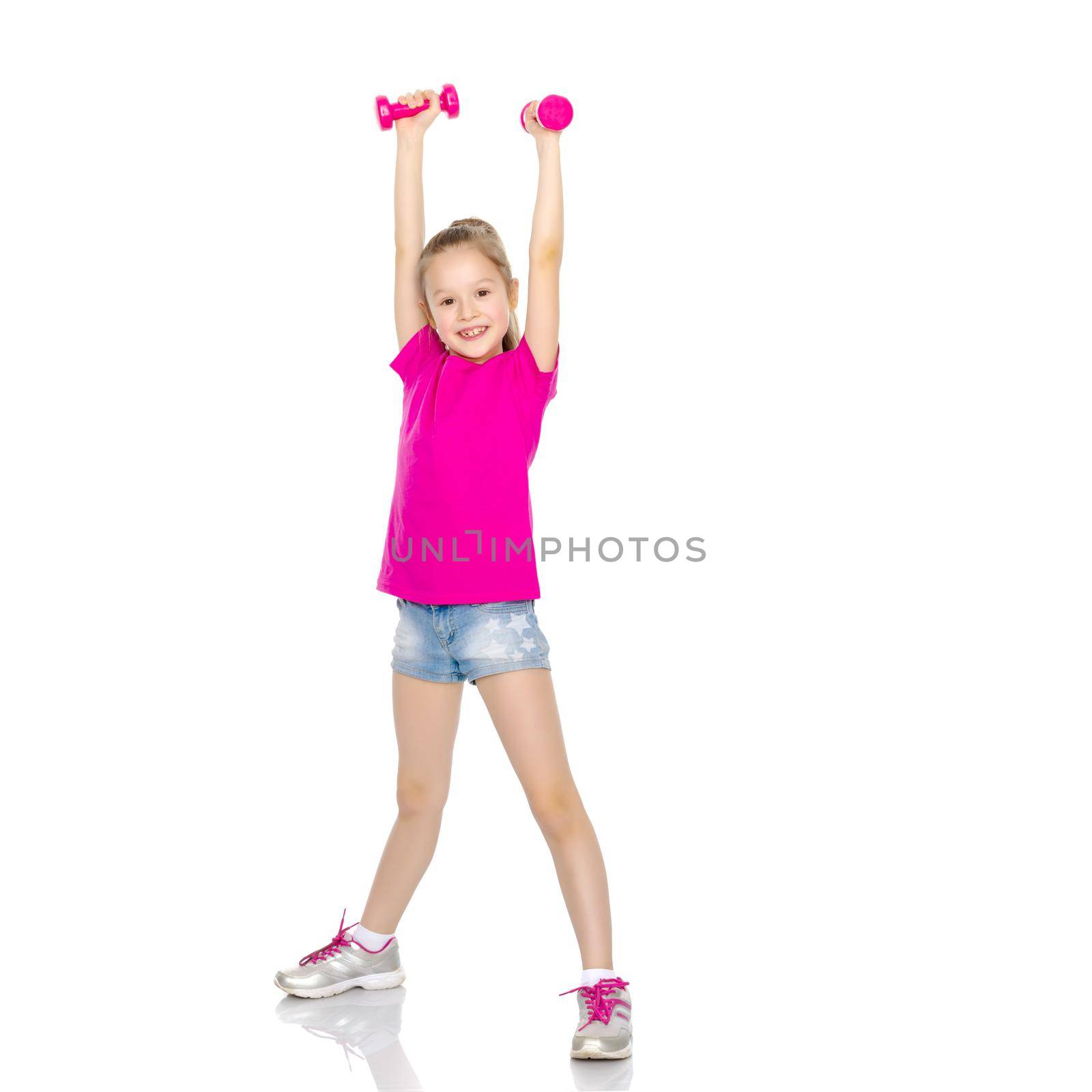 A cute little girl doing exercises with dumbbells. The concept of strength, health and sport. Isolated on white background.