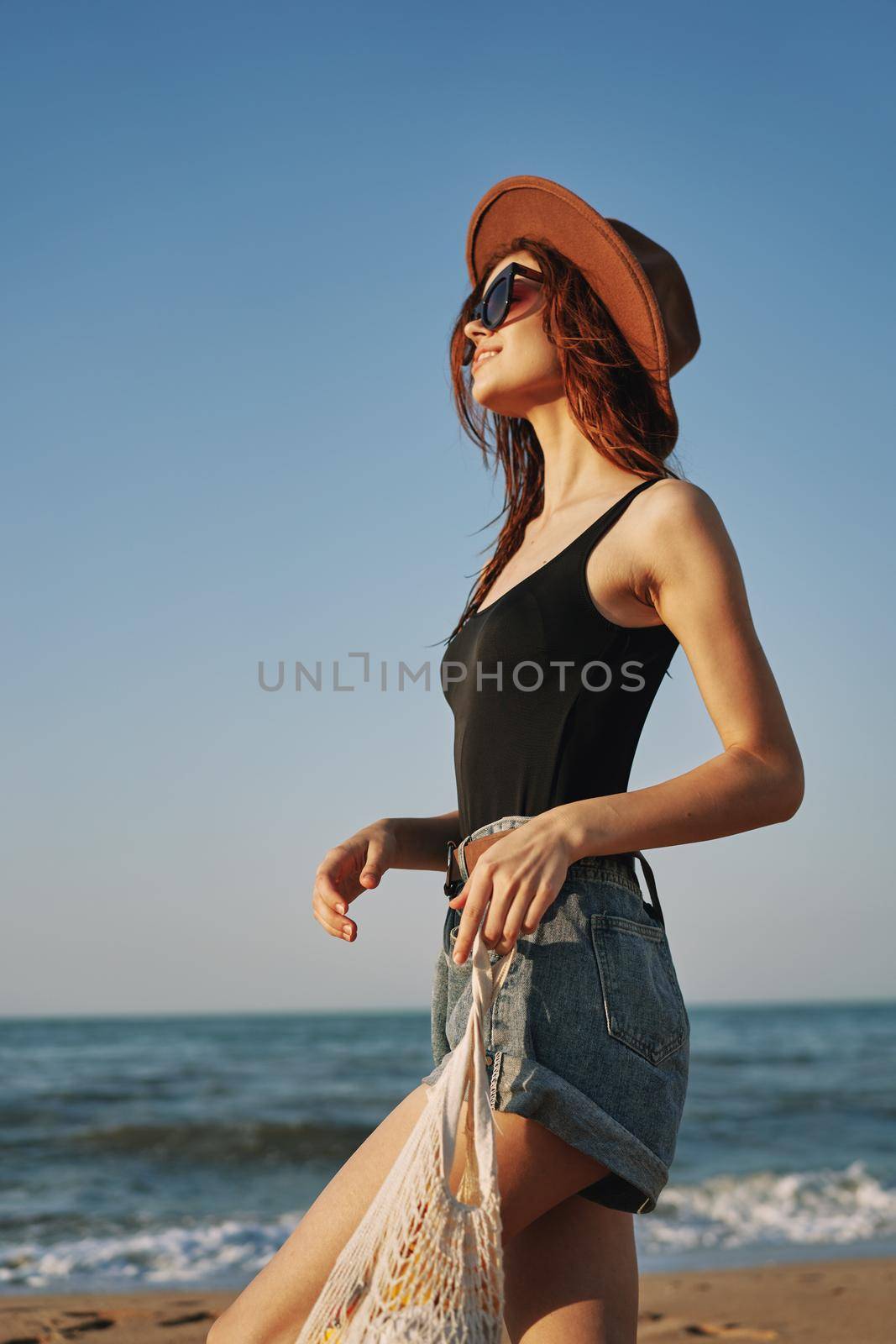 cheerful woman in a hat with sunglasses walking with a bag. High quality photo