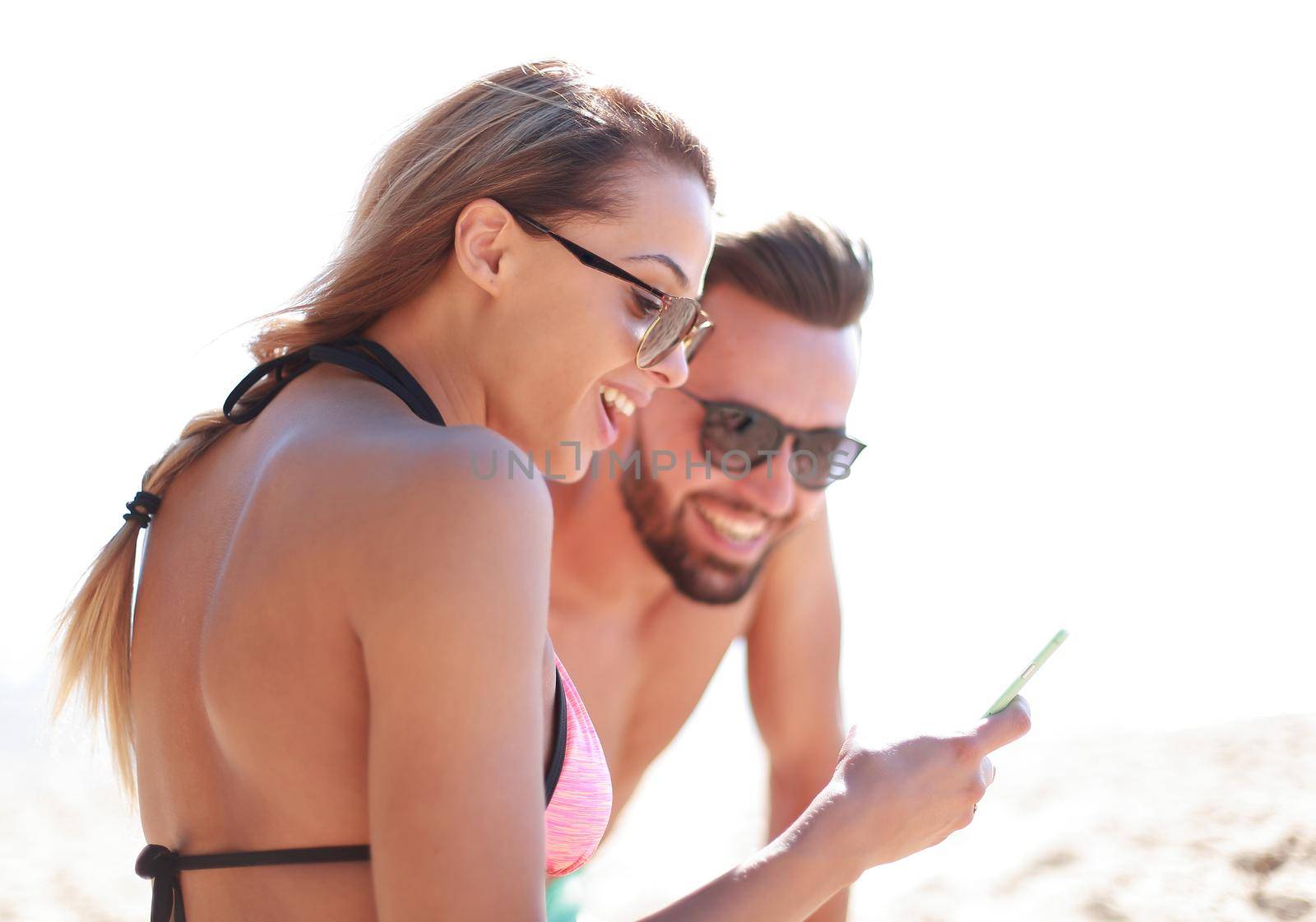 Romantic couple browsing their photos on the beach