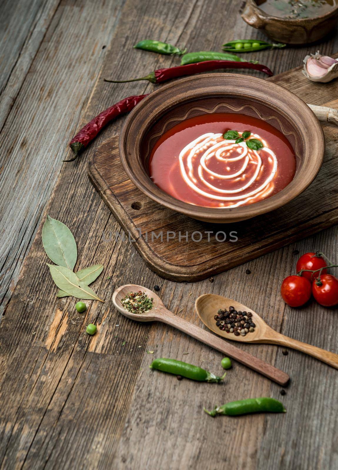 Served bowl of tomato soup with toasted bread and beans, dark wooden table, topview
