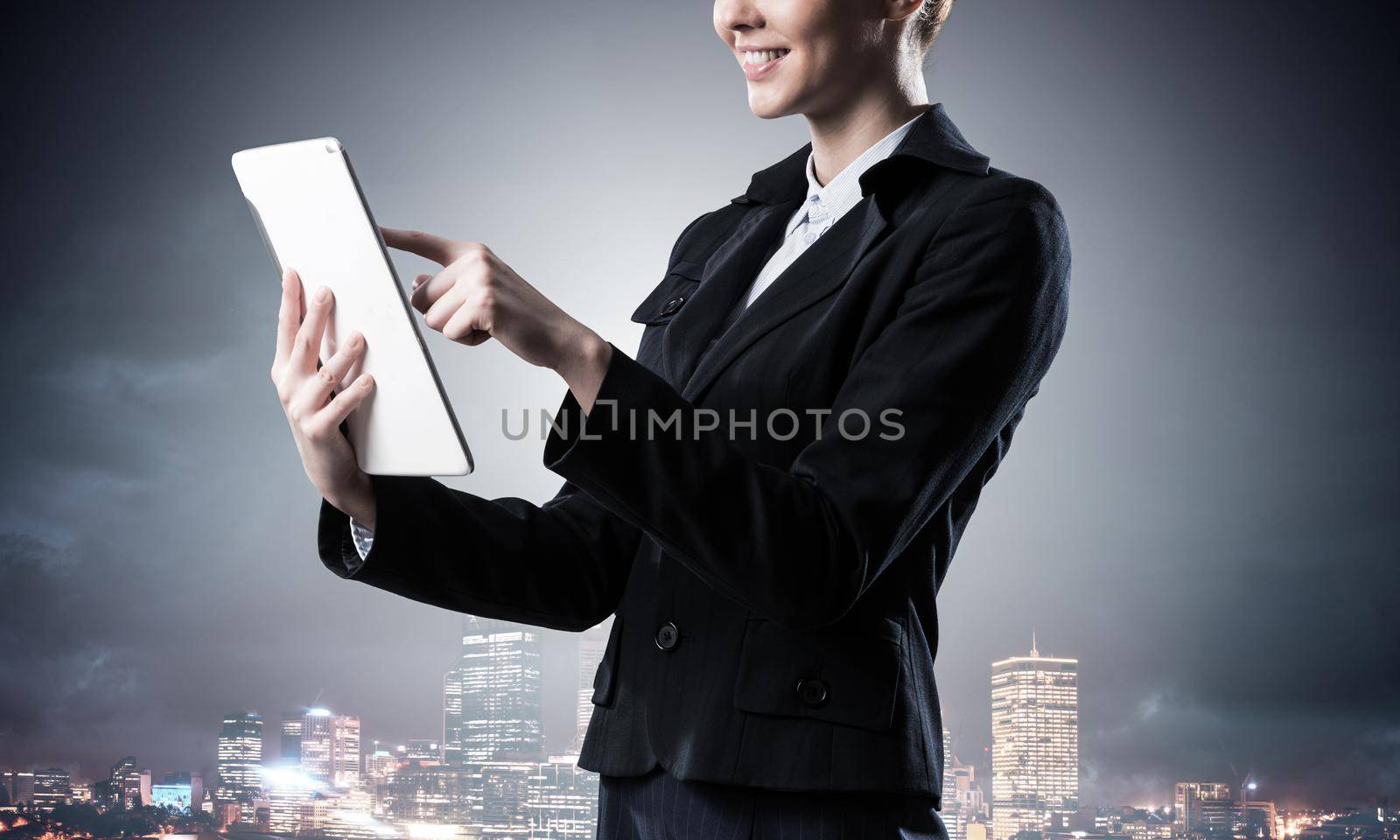 Businesswoman using tablet computer. Double exposure concept with night city and woman in business suit. Real estate investment. Digital technology in property management and development company.