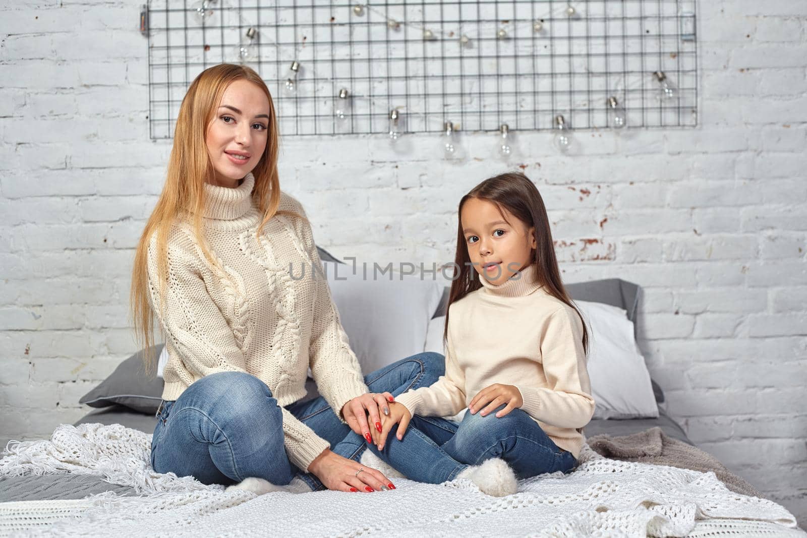 Happy loving family. Mother and her daughter child girl playing and hugging on bed