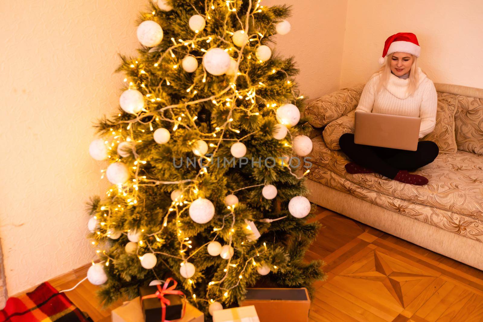 woman with laptop on the background of a Christmas tree accepts online congratulations merry christmas