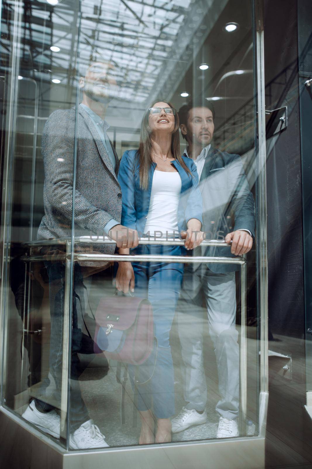 Business people in a large glass elevator in a modern office by asdf