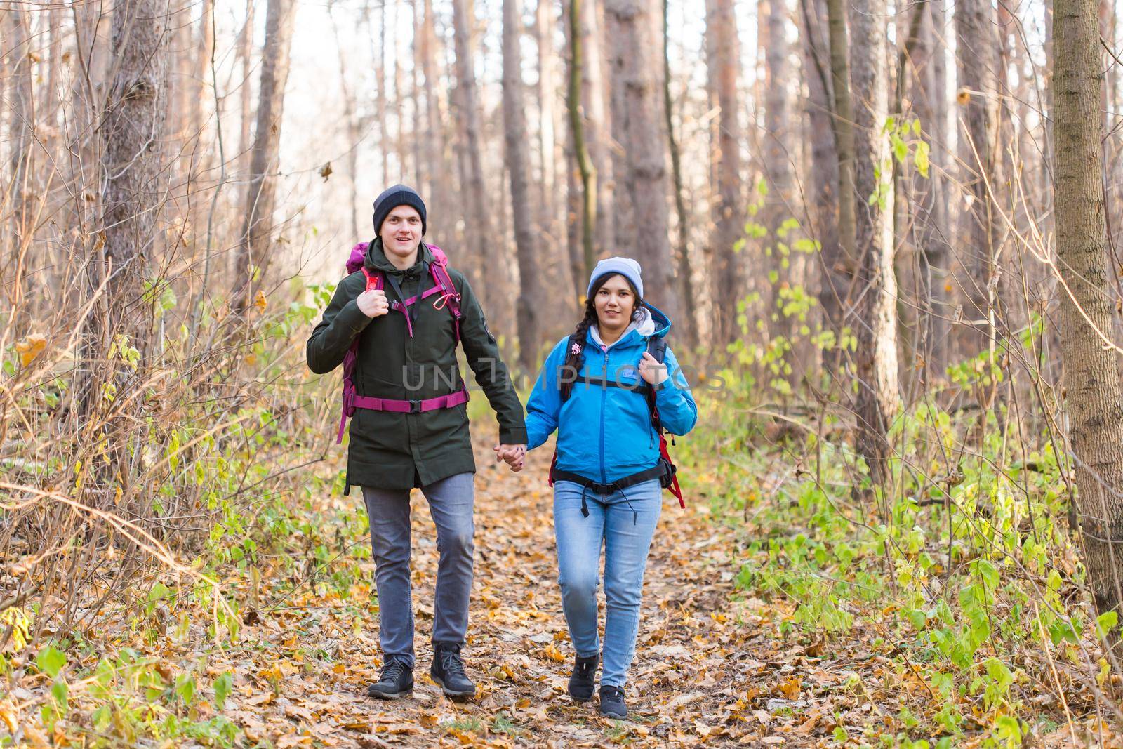 Travel, tourism, hike and nature concept - Tourists walking in park with backpack dressed in blue and black jackets.
