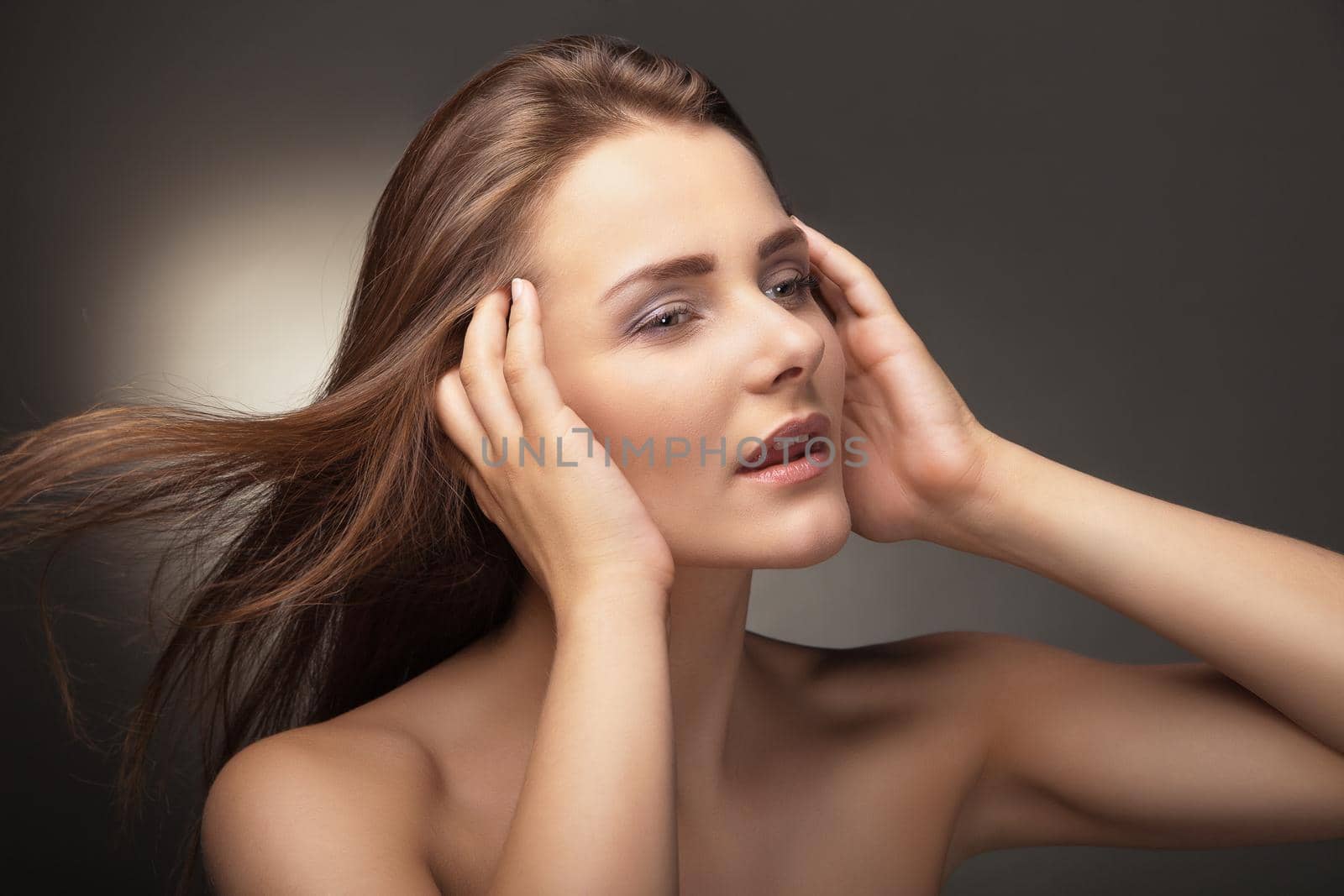 Sensual young woman with beautiful long brown hairs, posing. Studio shot