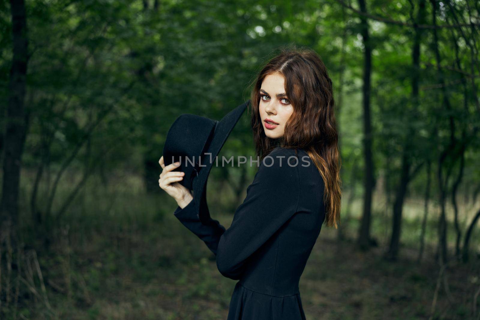 woman in the forest in a black hat gothic style Witch costume. High quality photo