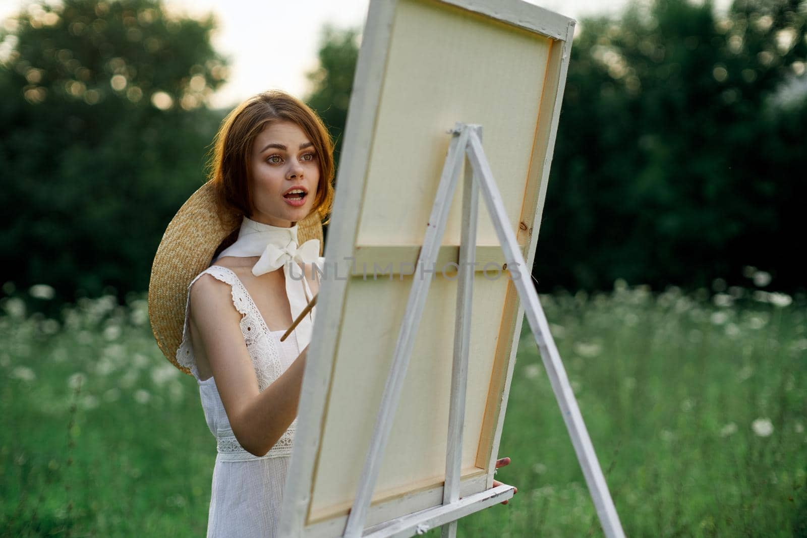 Woman in white dress paints a picture outdoors hobby creative. High quality photo