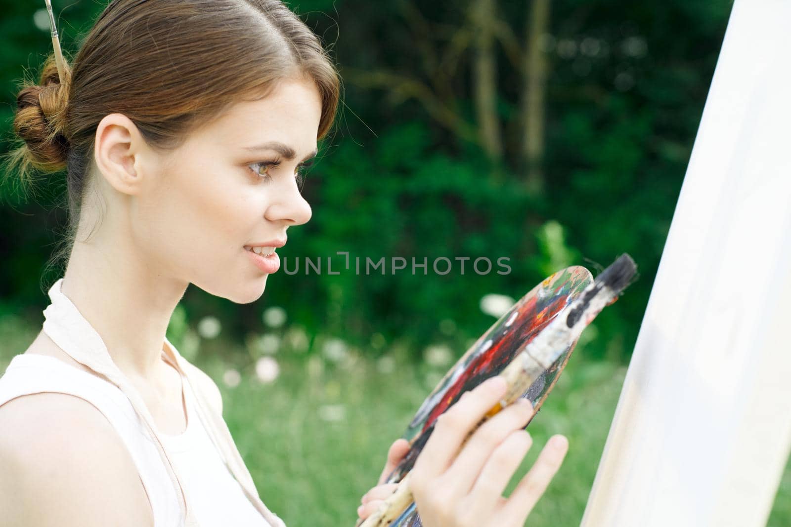 woman artist paints palette easel nature drawing. High quality photo