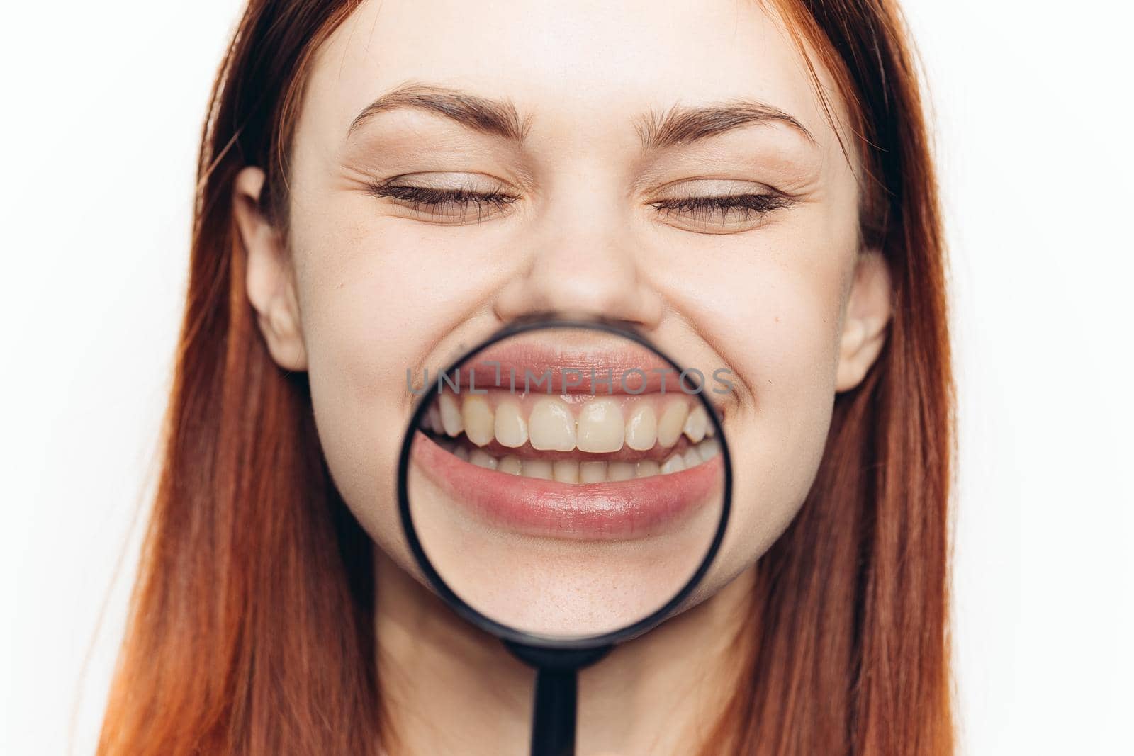 pretty woman grimacing with magnifying glass near face close-up. High quality photo