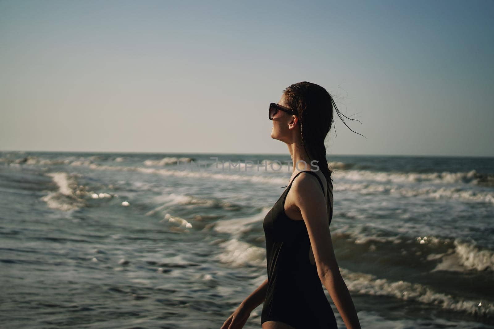 woman in black swimsuit walking on the beach ocean summer. High quality photo