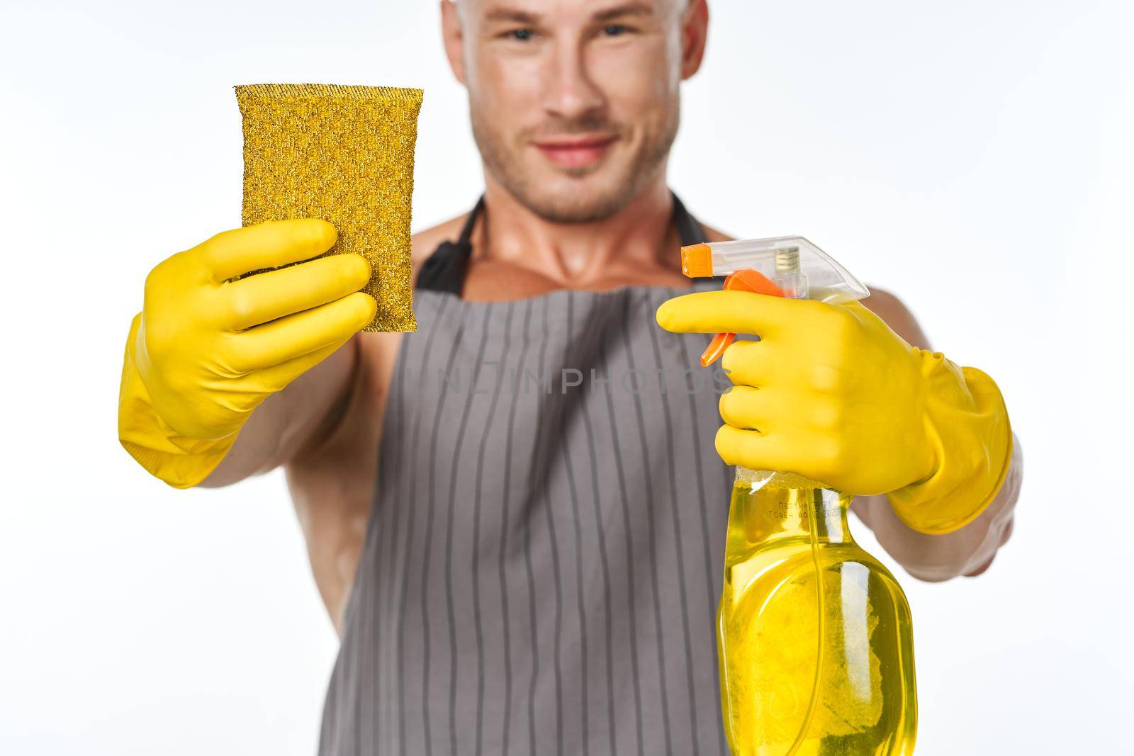 pumped up man in an apron with rubber gloves detergents. High quality photo