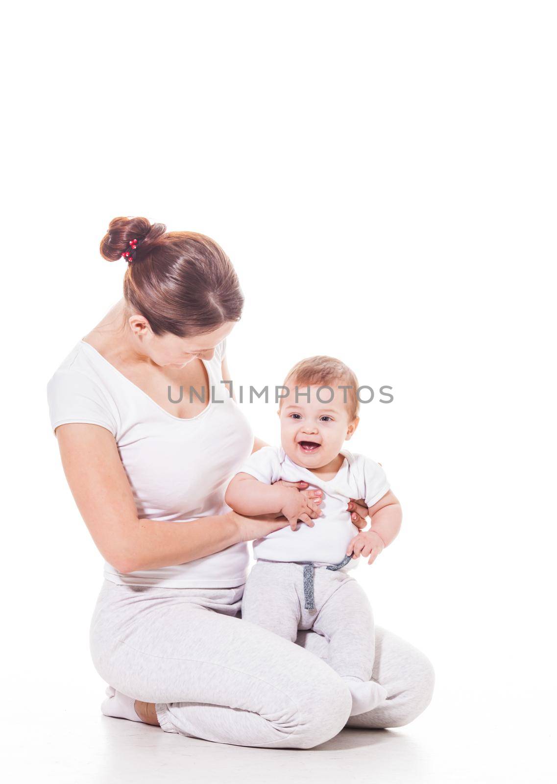 Close up view of attractive young mother with her baby wearing white on a white background