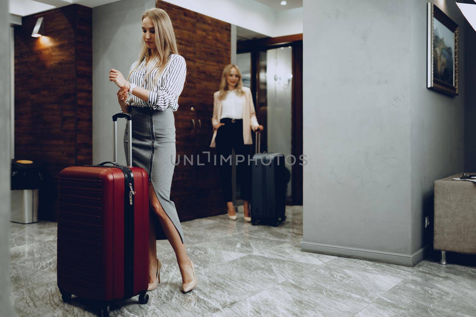Two young women in formal clothes entering hotel lobby. Business trip concept