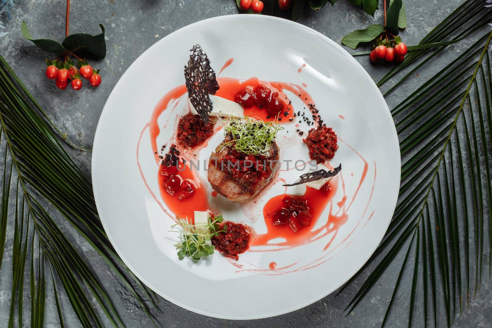 Appetizing beef in sweet sauce close up. Chopped beef meat in cherry sauce with vegetables on plate. Delicious european cuisine.