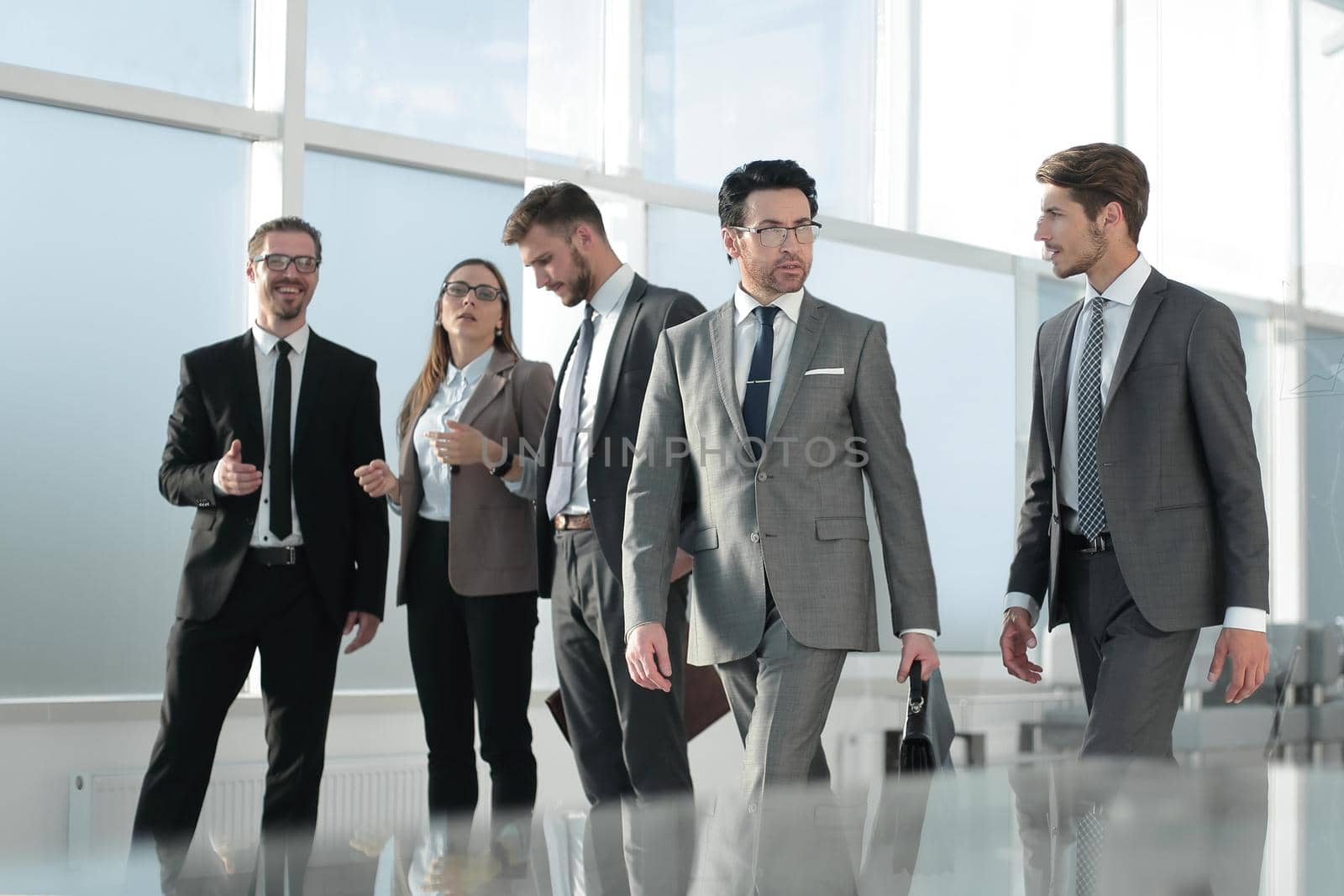 Confident businessman with colleagues strolling in the office