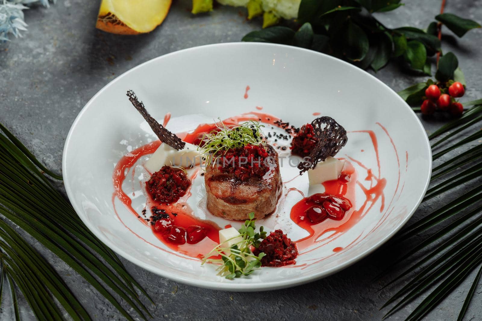 Appetizing beef in sweet sauce close up. Chopped beef meat in cherry sauce with vegetables on plate. Delicious european cuisine.