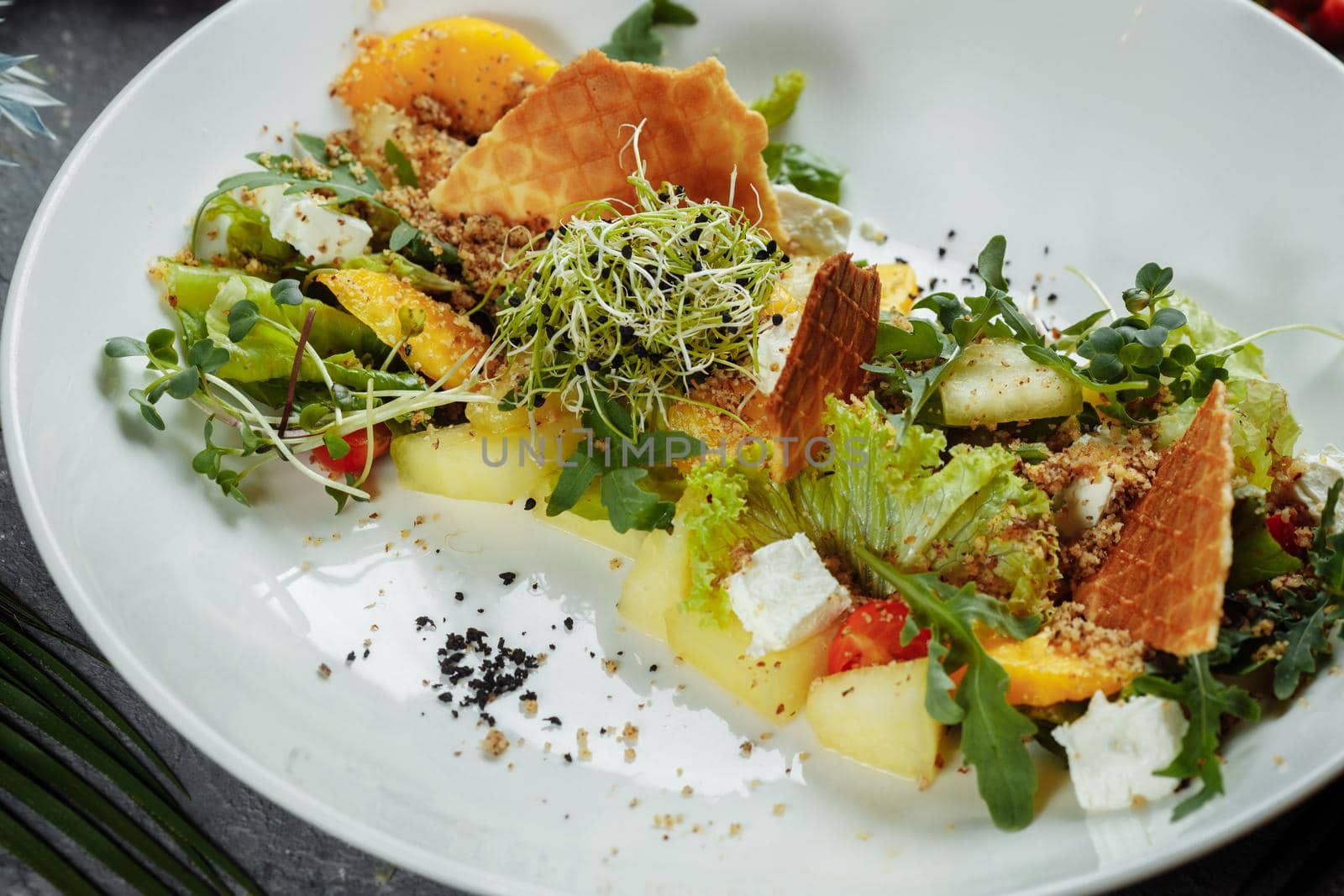 Summer diet salad with leaves of lettuce, watermelon, peach and feta cheese. On a light blue background copy space.