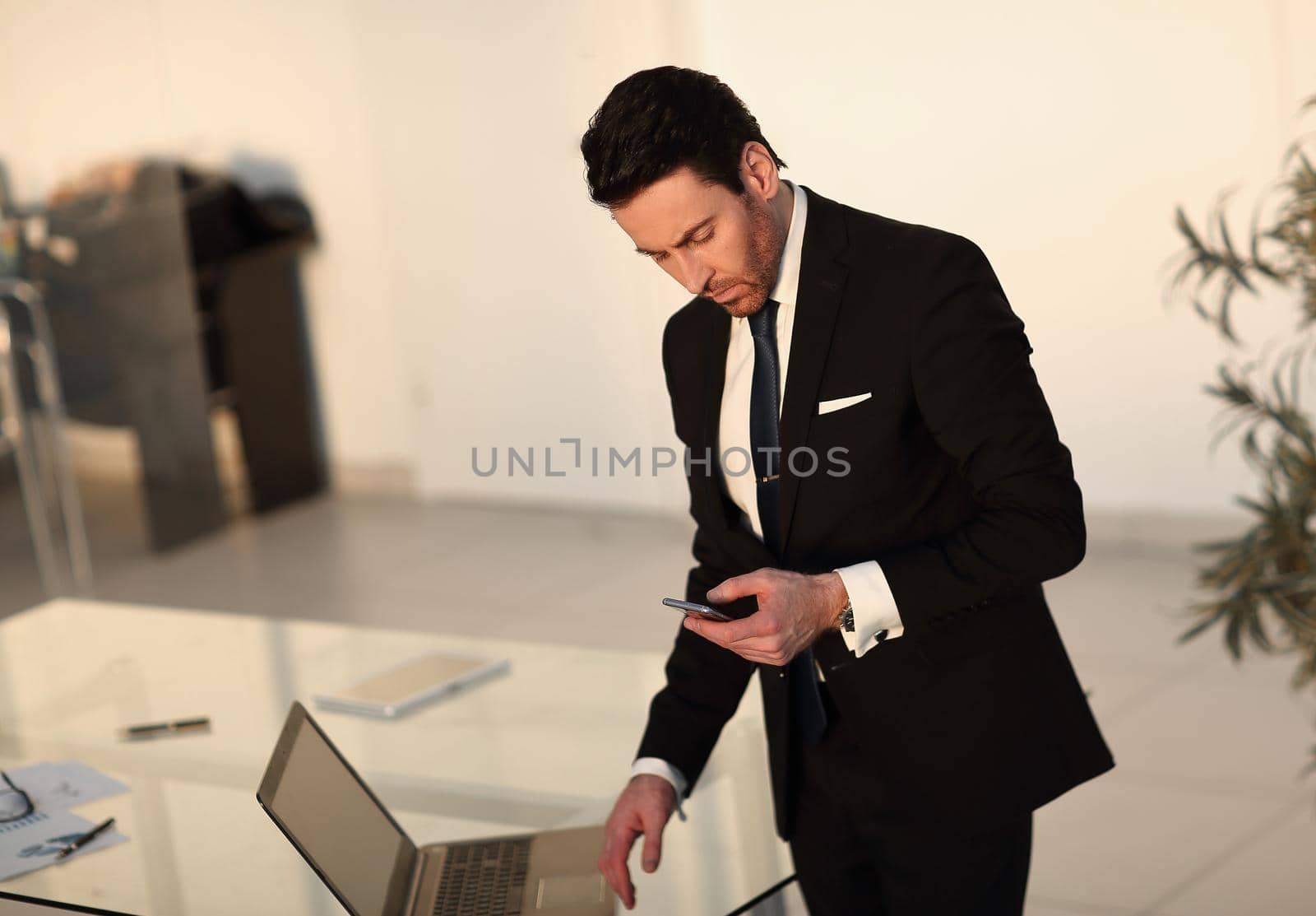 businessman reading text message on smartphone ,while standing in the office by asdf