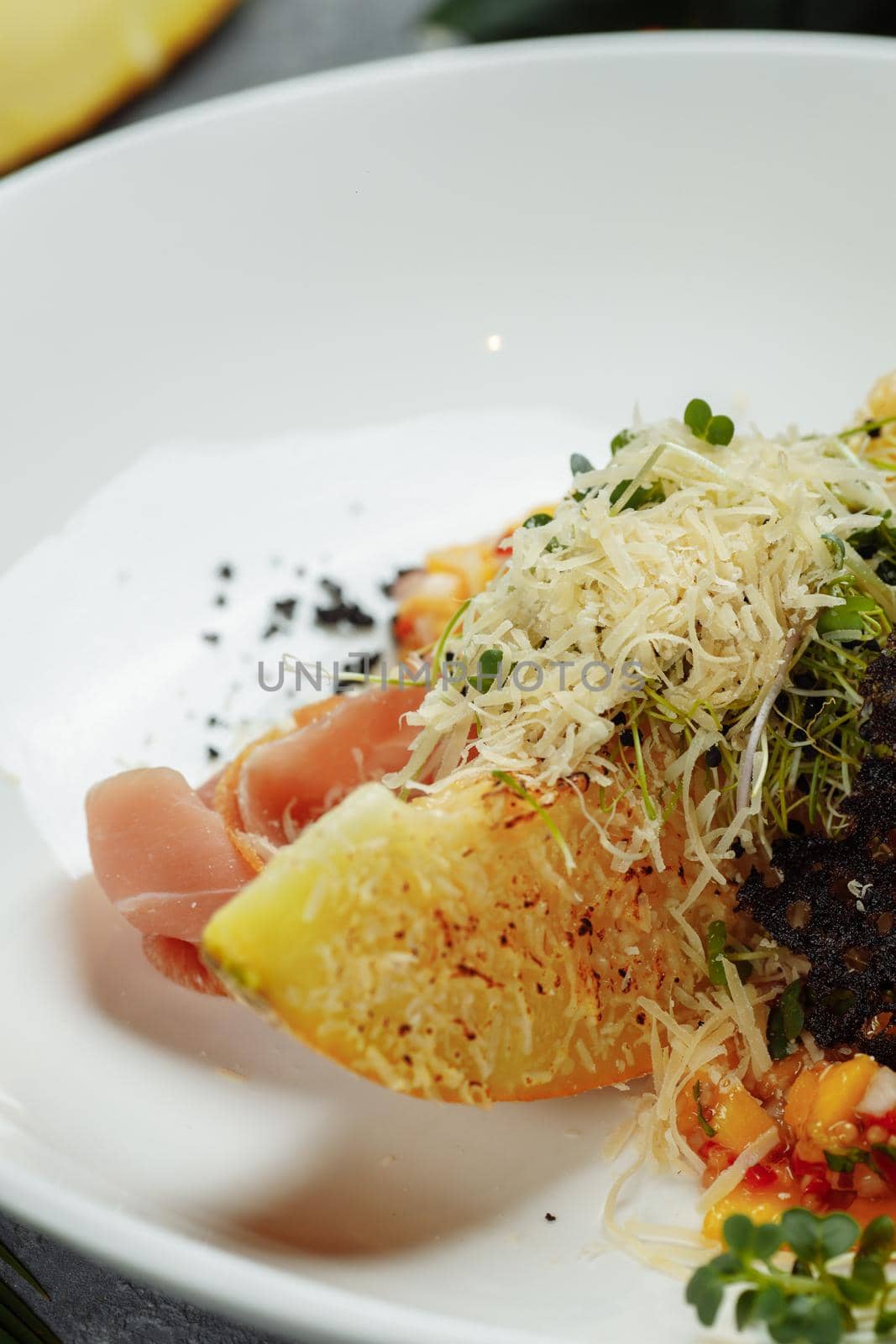 baked melon with parmesan and jamon on a white plate.