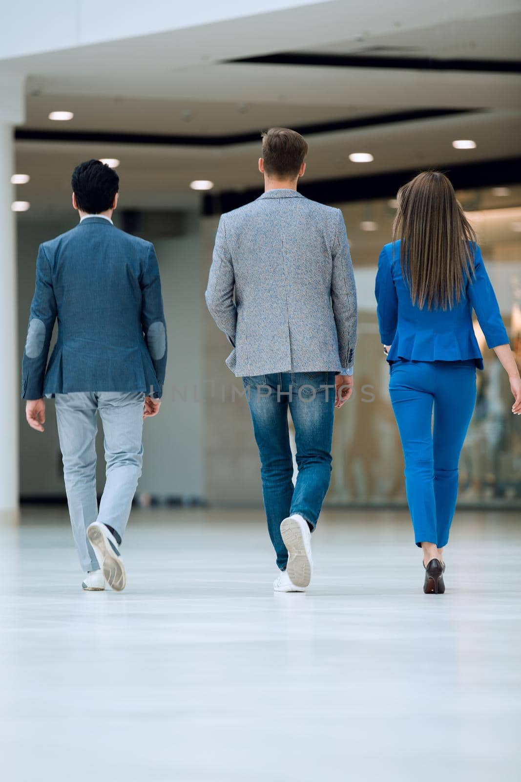 rear view.business colleagues walk in the office hall.photo with copy space