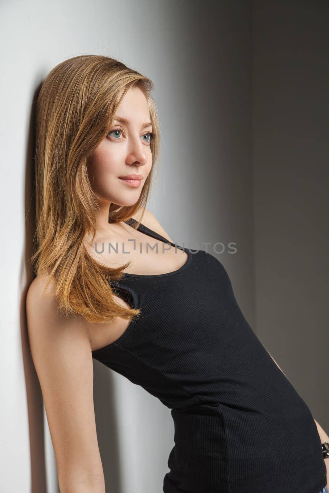 Beautiful young woman wearing jeans and black t-shirt over gray background