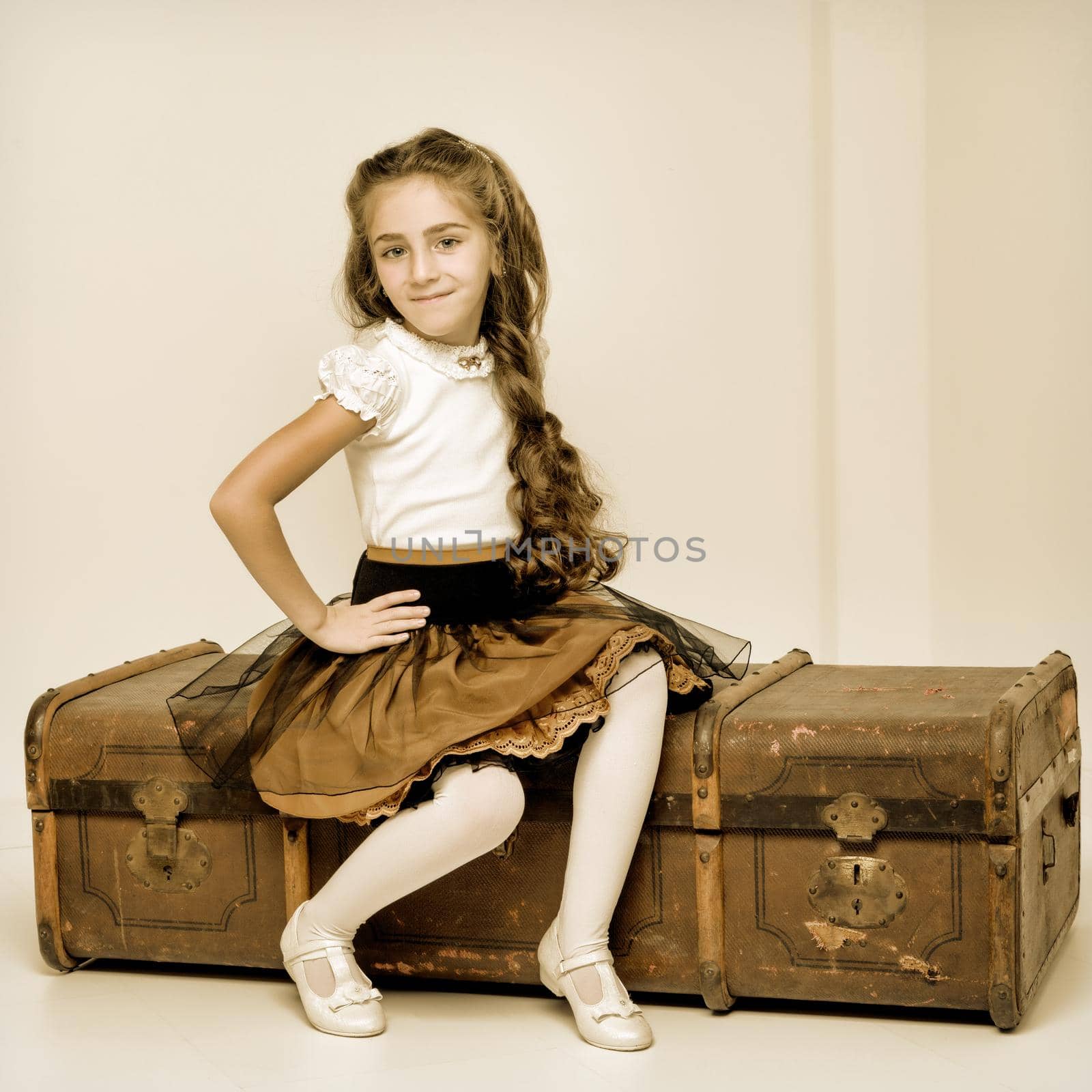 A little girl is sitting on a wooden box. by kolesnikov_studio