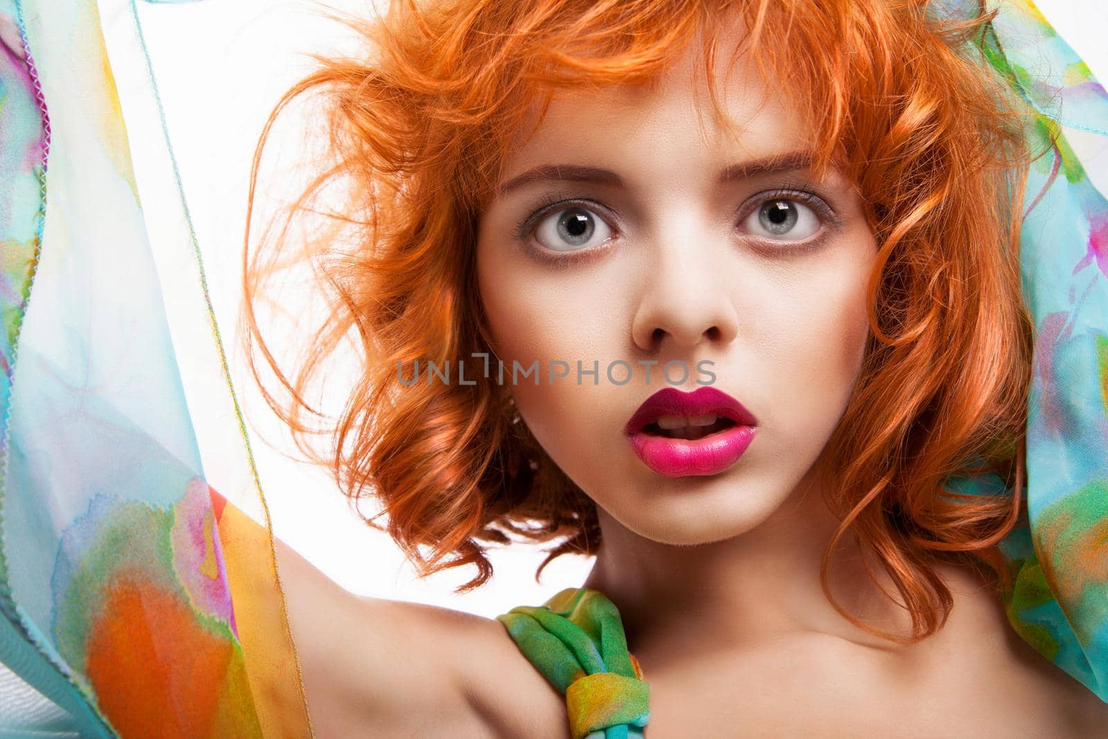 Girl with beautiful red hair and colorful dress and fabric over white background