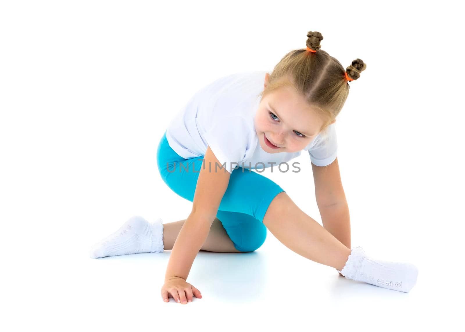 A sweet little gymnast girl performs an acrobatic element on the floor. The concept of sport, healthy lifestyle. Isolated on white background.