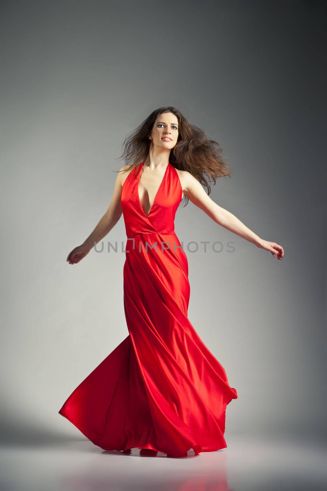 Gorgeous young ballet dancer wearing red dress over dark grey background