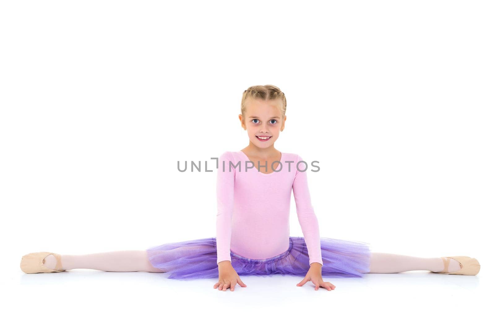 A little girl performs a gymnastic twine. The concept of fitness and sports. Isolated on white background.