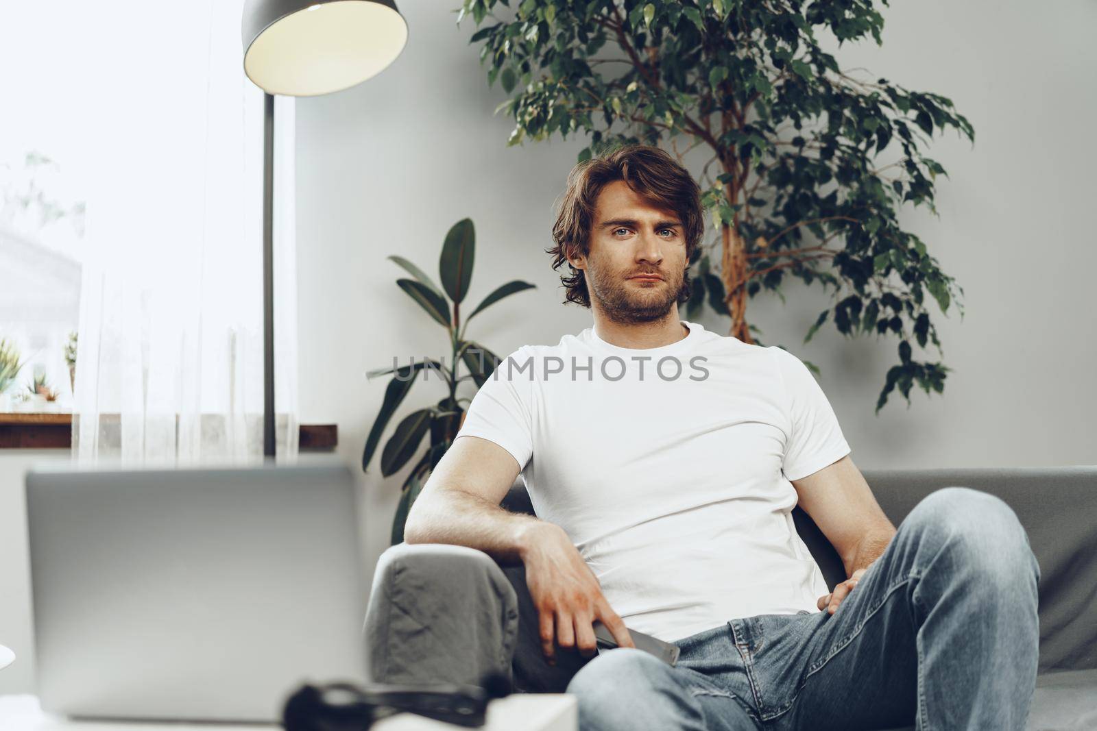 Relaxed casual man sitting on the sofa and looking at camera, man portrait