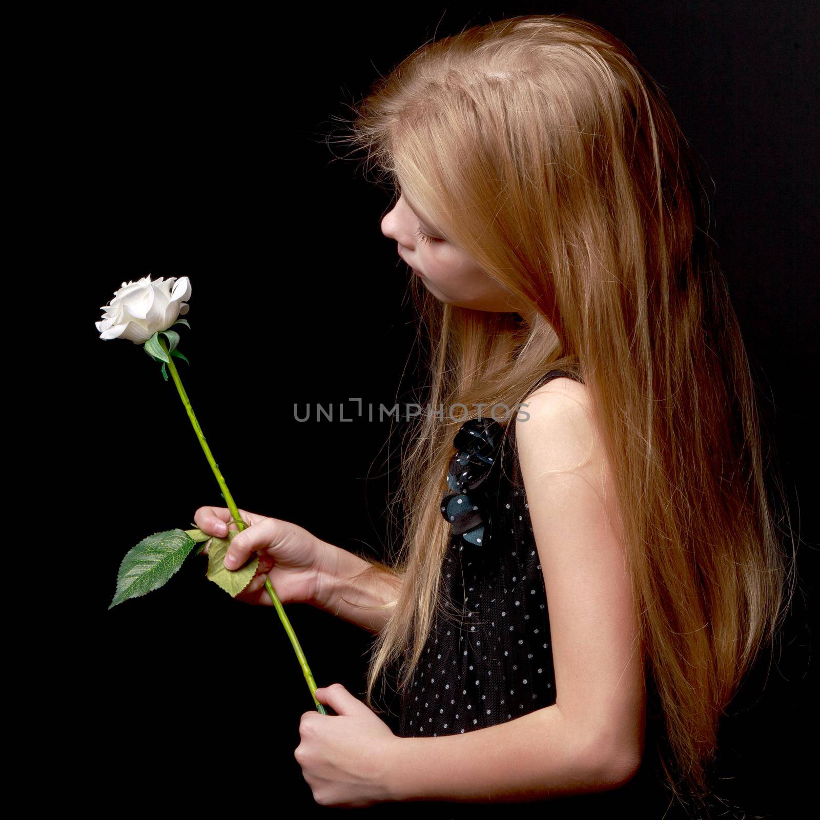Cute little girl with white flower on a black background. The concept of style and fashion.