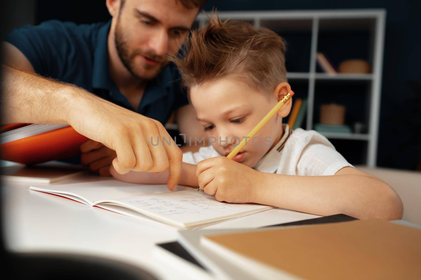Father helping his little son with school homework close up