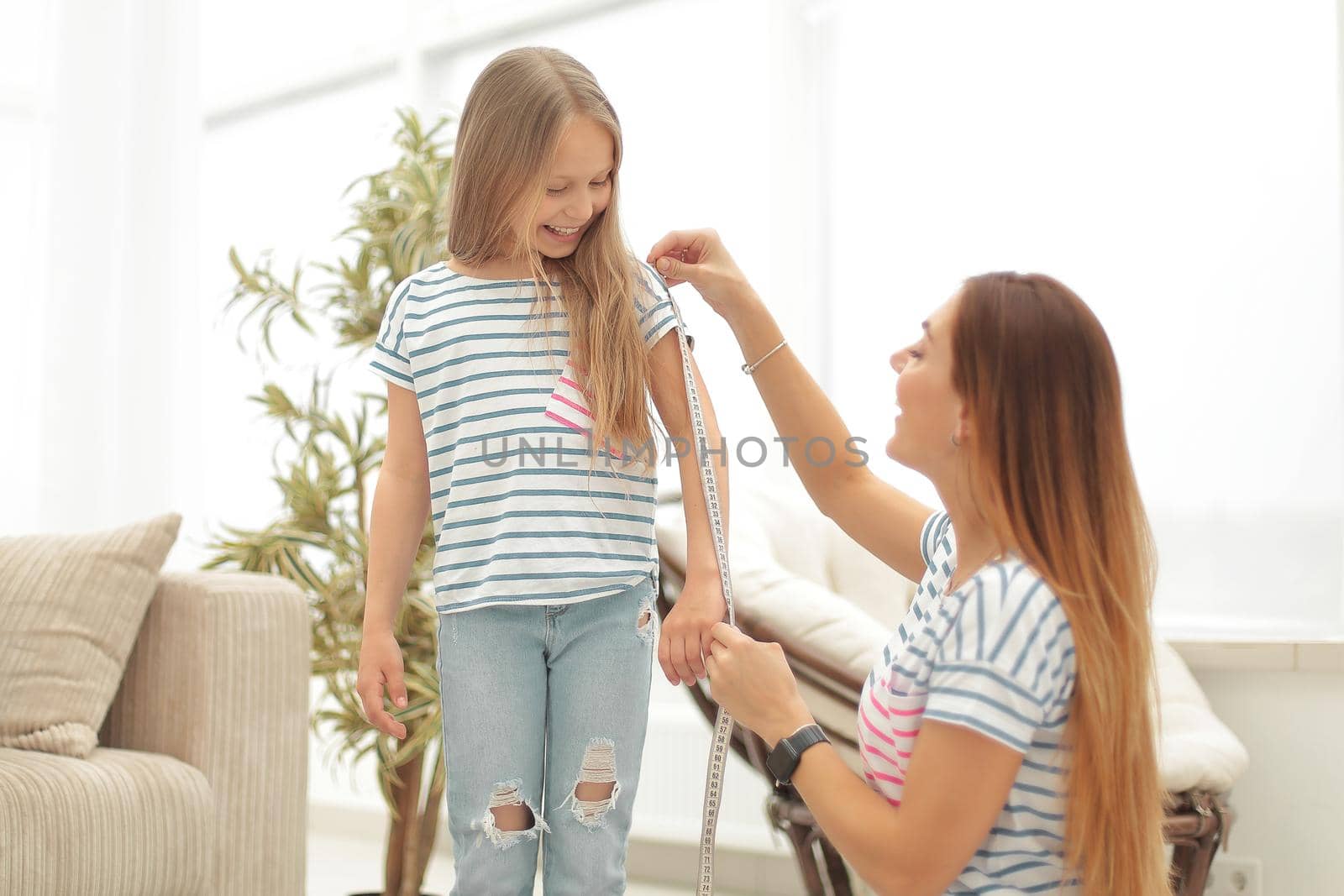 attentive mother and daughter make measurements for new clothes by asdf