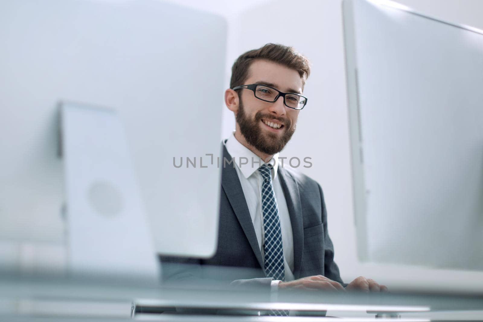 businessman working on a computer sitting at his Desk by asdf