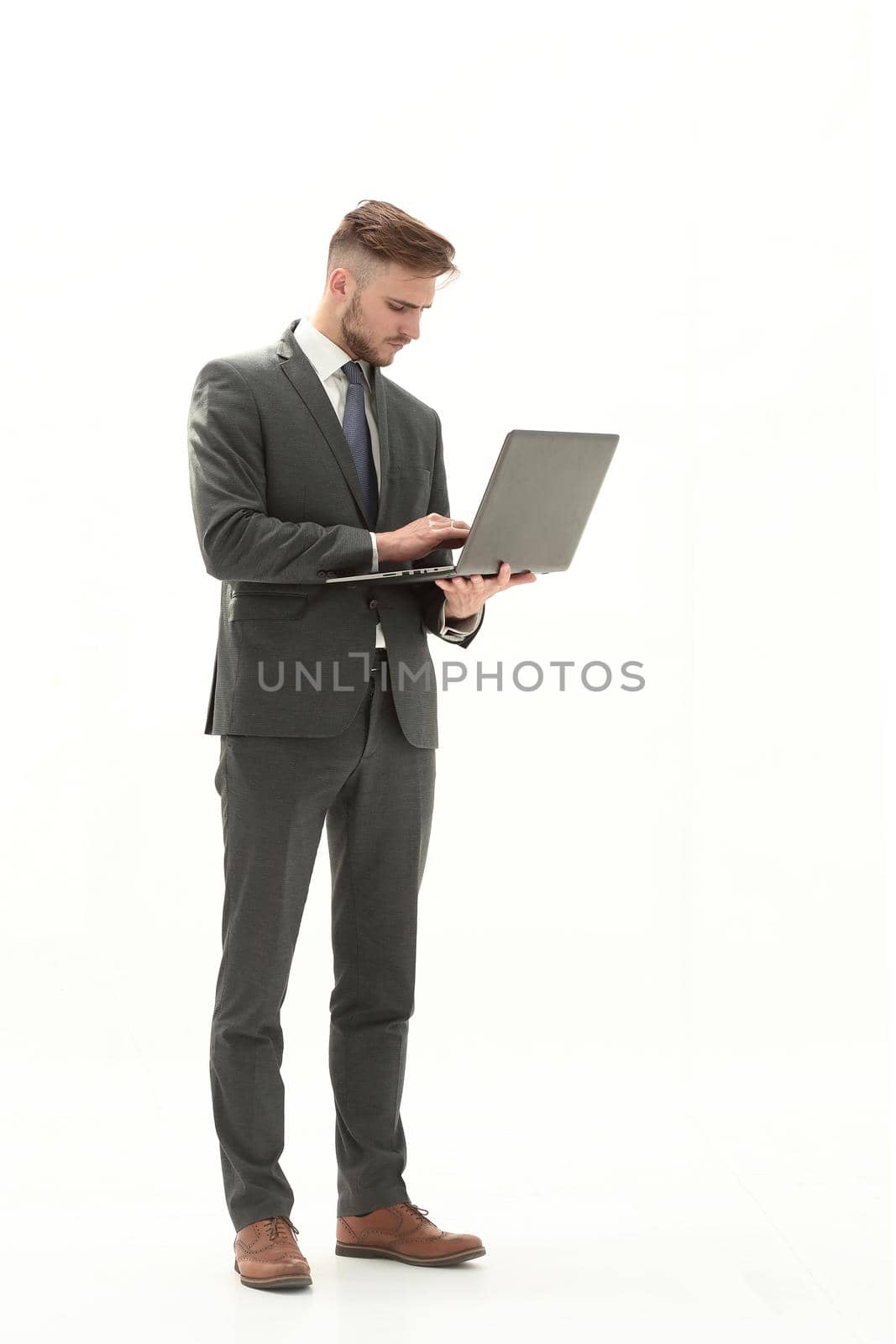 Full-length portrait of a businessman standing and using laptop isolated on a white background