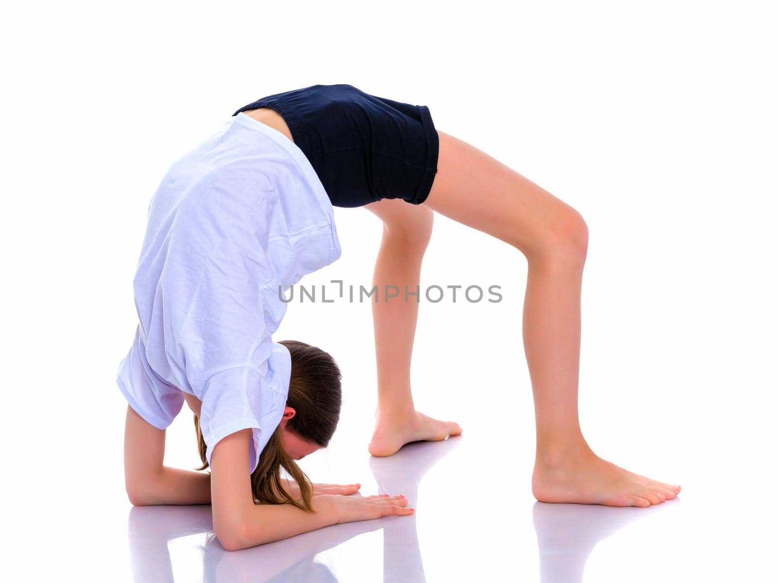 A girl gymnast performs an acrobatic element on the floor. The concept of childhood, sport, healthy lifestyle. Isolated on white background.