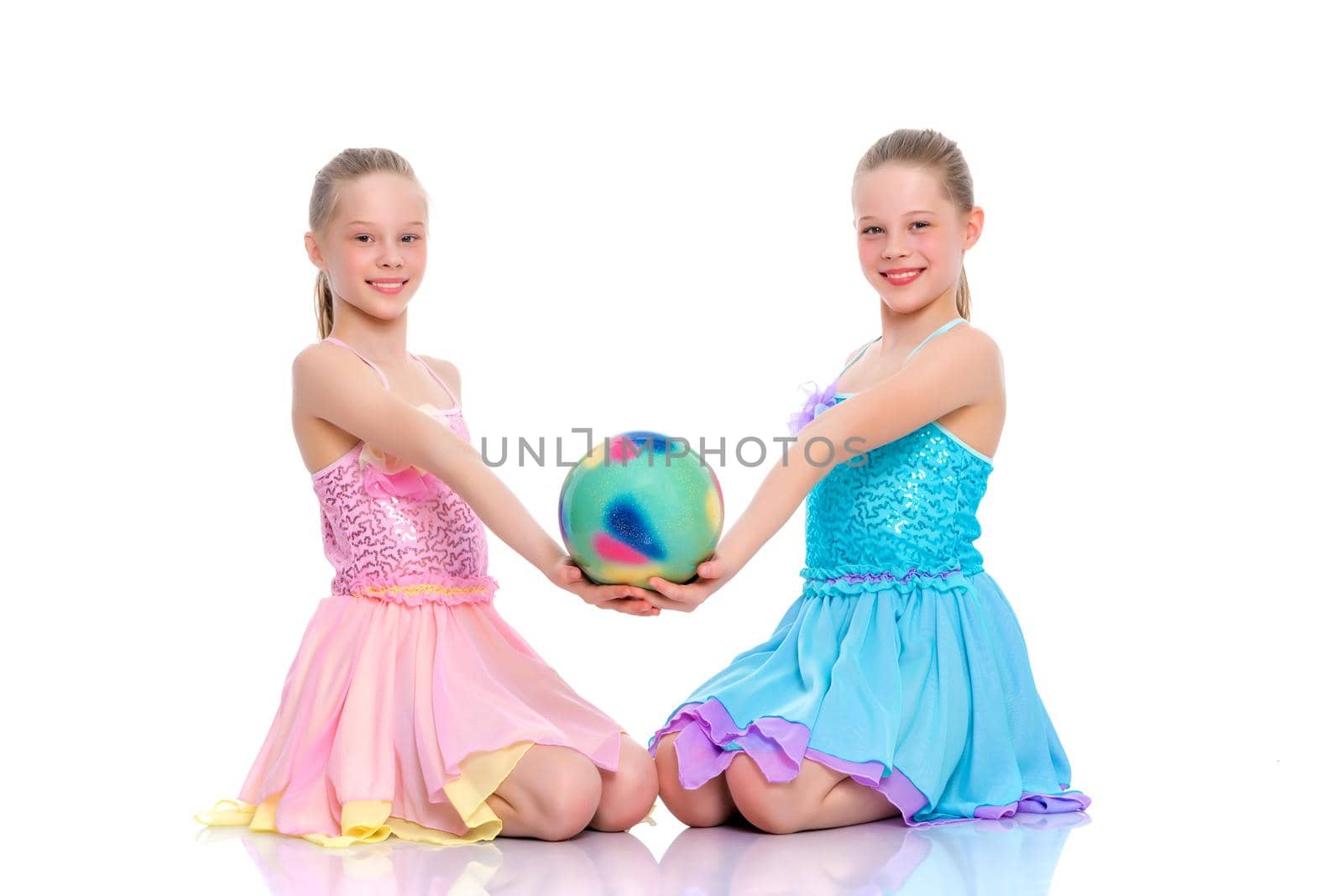 Two cheerful little girls gymnasts in competitions, perform exercises with the ball. The concept of children's sports, fitness, healthy lifestyle. Isolated on white background.